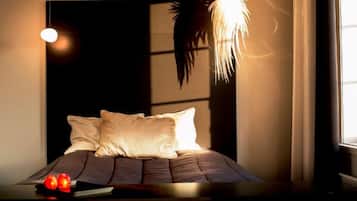 Una camera da letto moderna con un letto, cuscini e un'originale lampada a sospensione.
