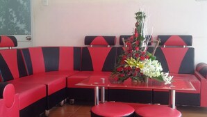 A modern hotel room with a red and black sectional sofa, a glass coffee table, and two red ottomans. - Seaside Hotel 2 (Nha Trang)