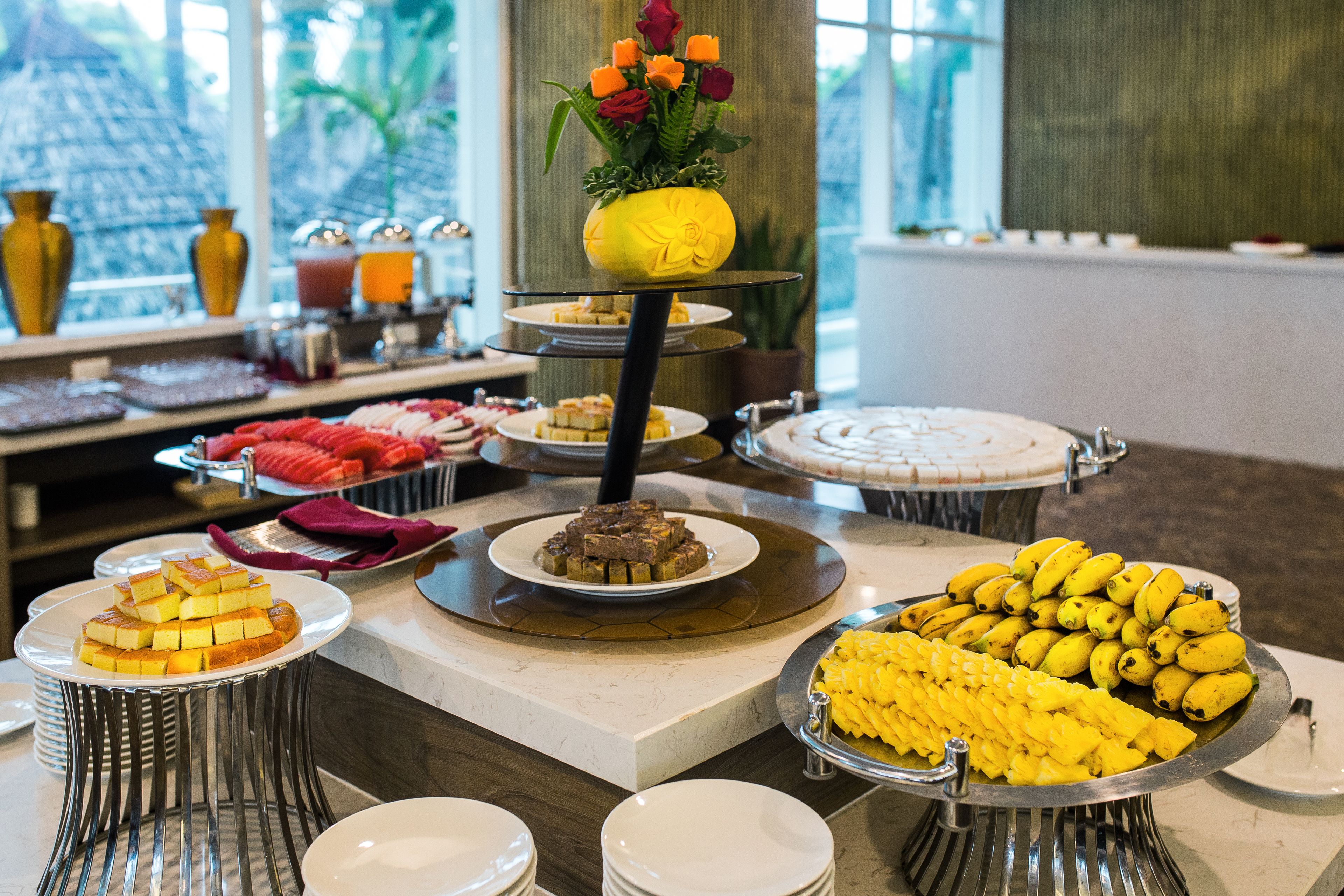 A buffet with various food items, including a banana display and a cake on a tiered stand.