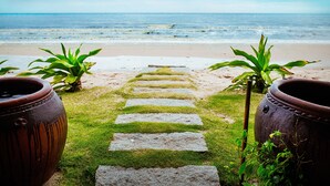 Un camino de piedra que conduce a una playa, con plantas en macetas a ambos lados.