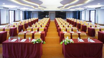 A conference room with rows of tables, each with a red tablecloth and yellow chairs.