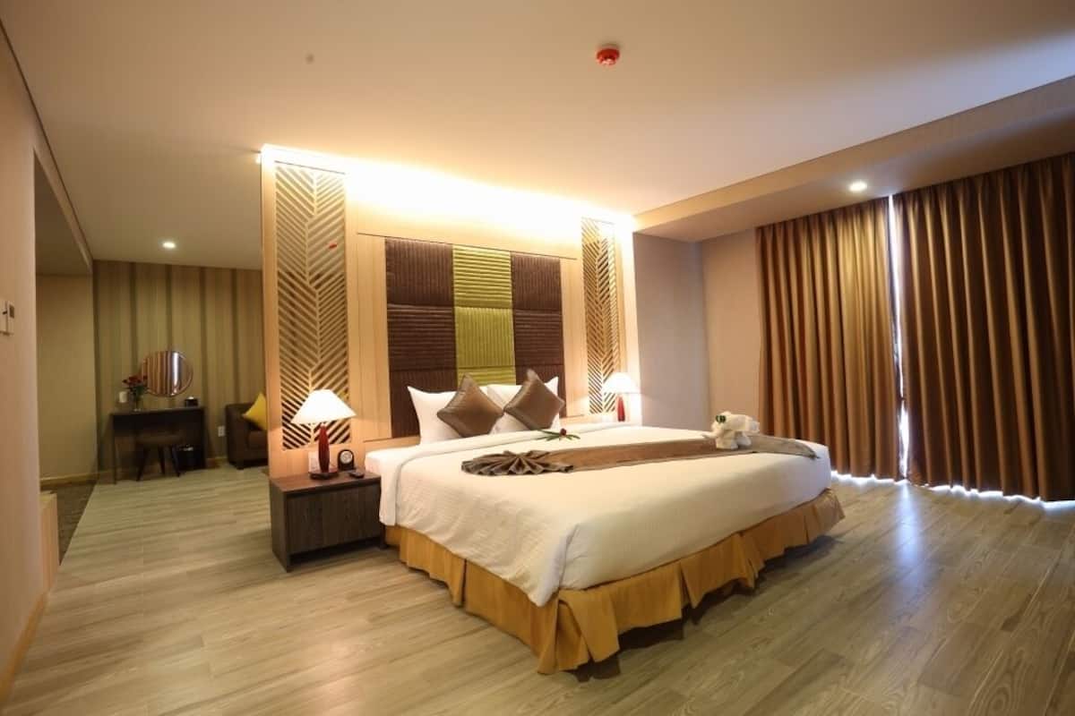 A hotel room with a large bed, bedside tables, a desk, and a chair.