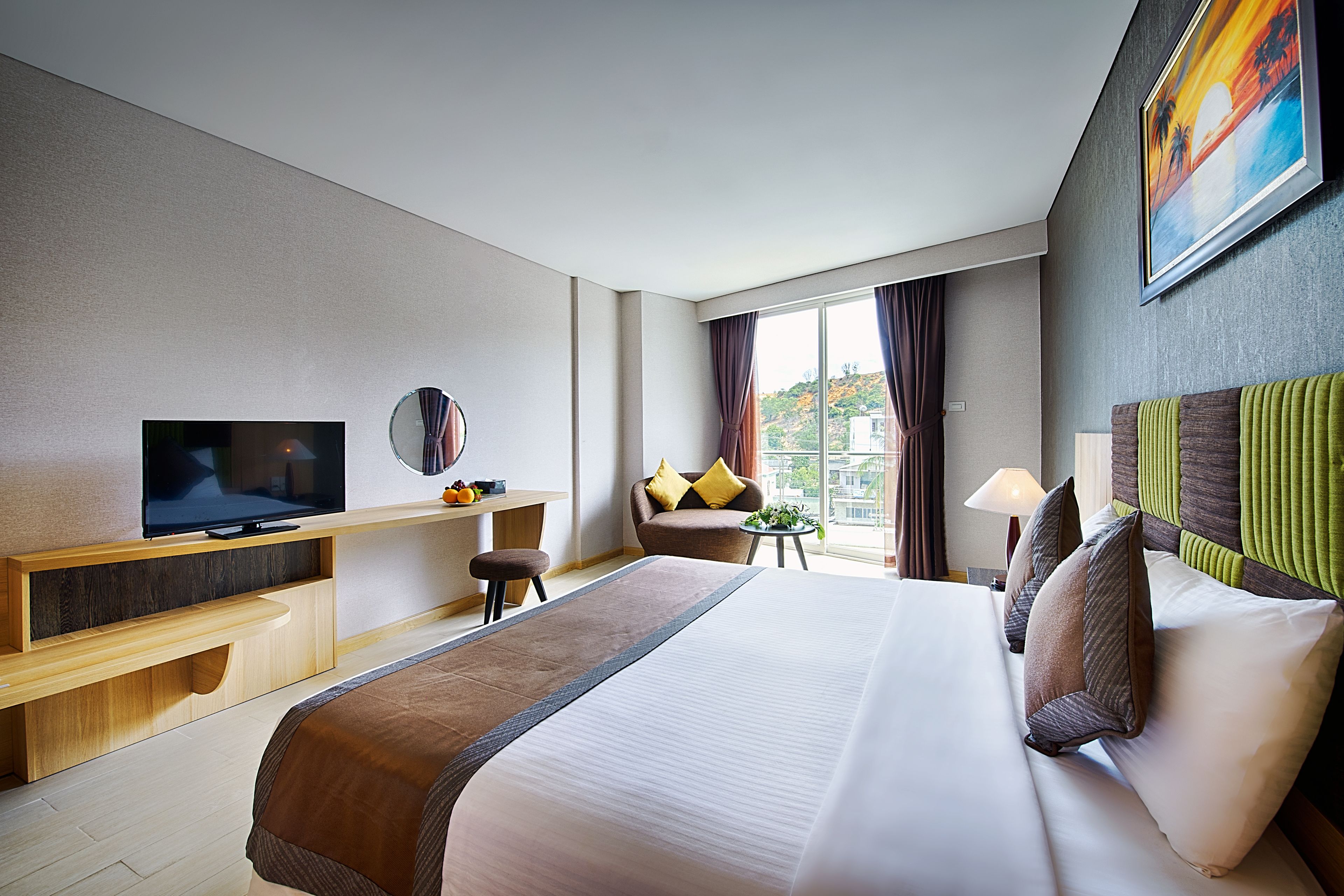 Una habitación de hotel con una cama grande, televisión, escritorio y vista a la ciudad desde la ventana.