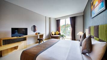 Ein Hotelzimmer mit einem großen Bett, einem Fernseher, einem Schreibtisch und Blick auf die Stadt durch das Fenster.