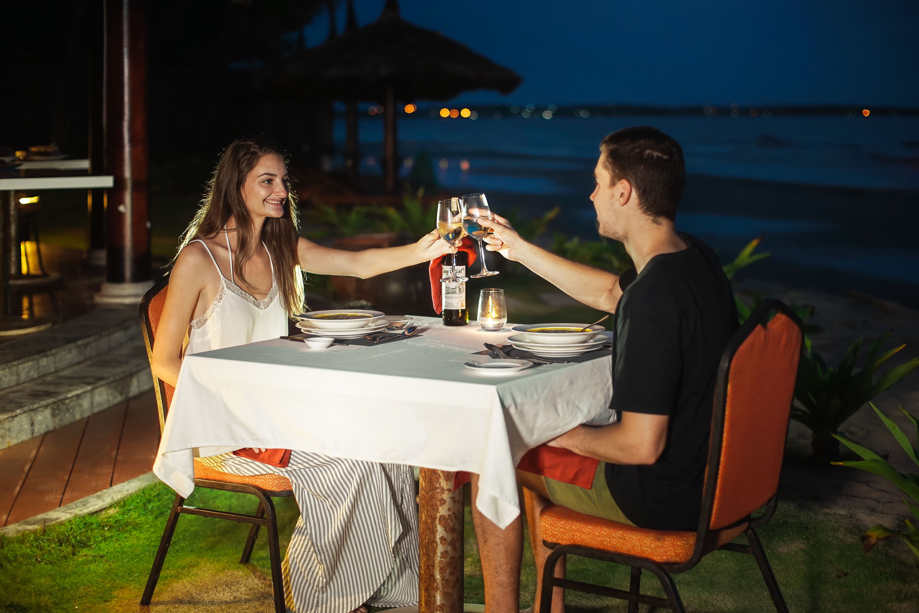 A table set for two with a view of the ocean at night.