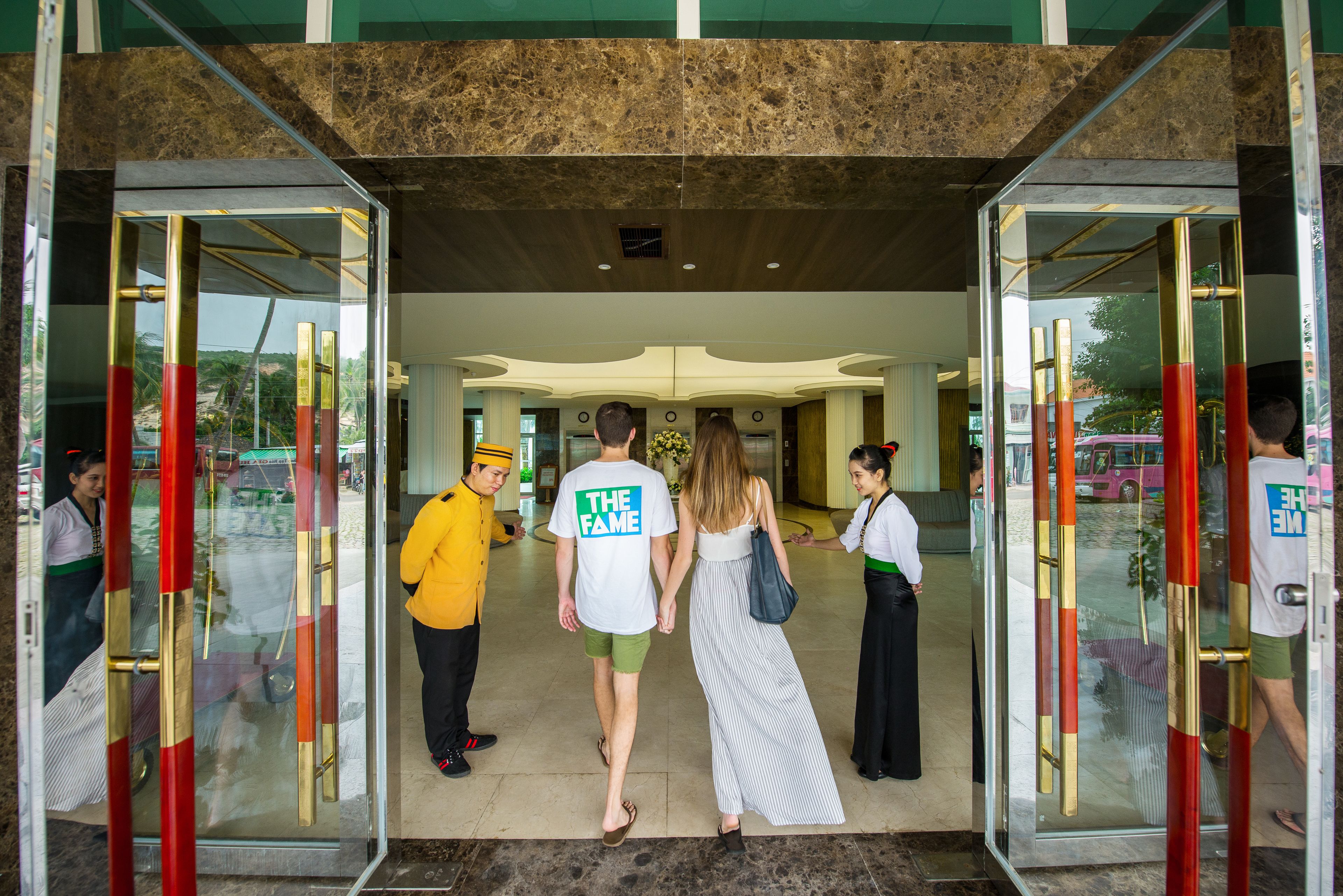 Entrada de hotel com portas de vidro, piso de mármore e design de interiores moderno.