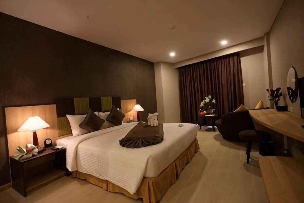 A hotel room with a large bed, bedside lamps, a desk, and a chair.