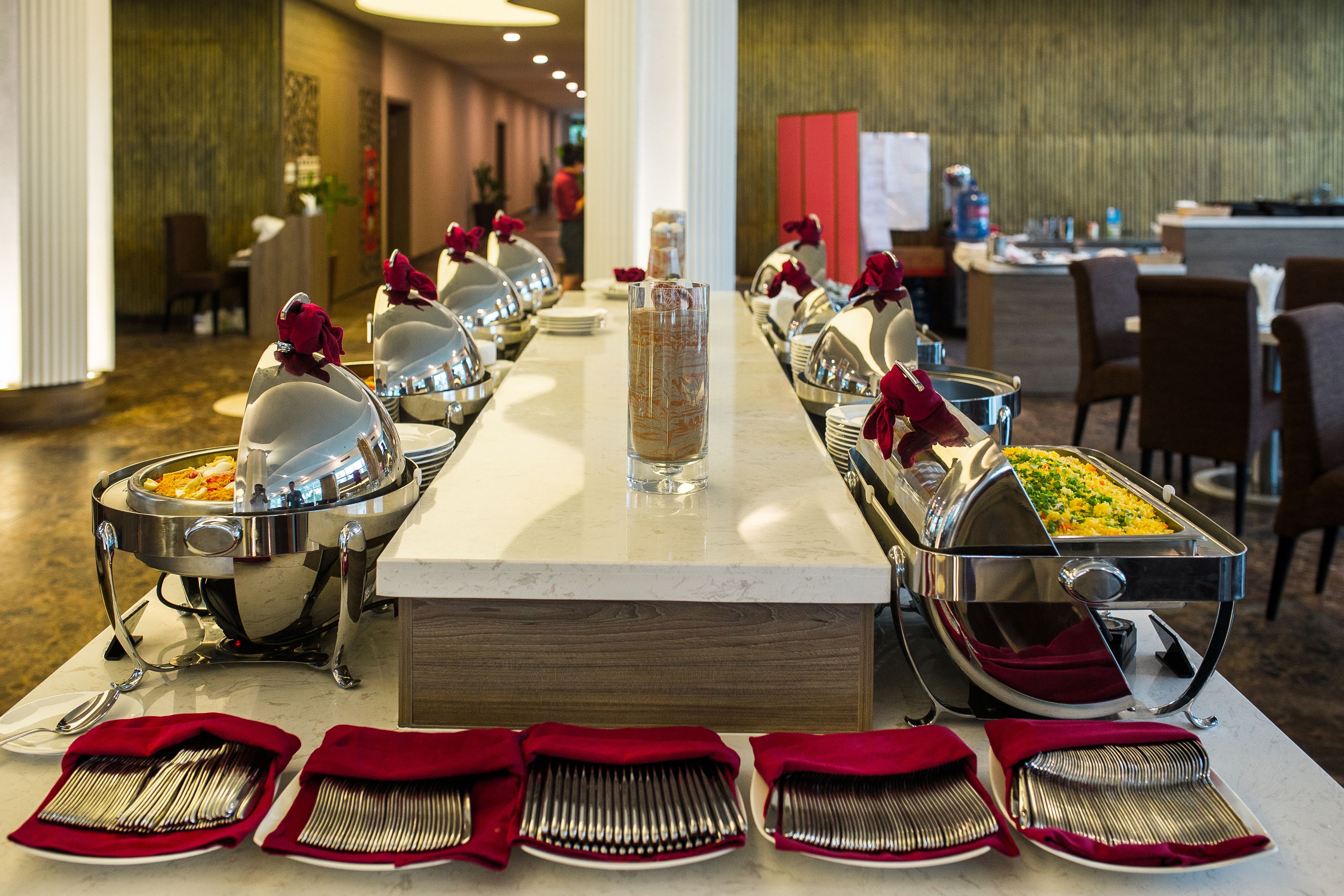 A buffet setup with multiple serving stations, each with a covered dish and a red napkin holder.