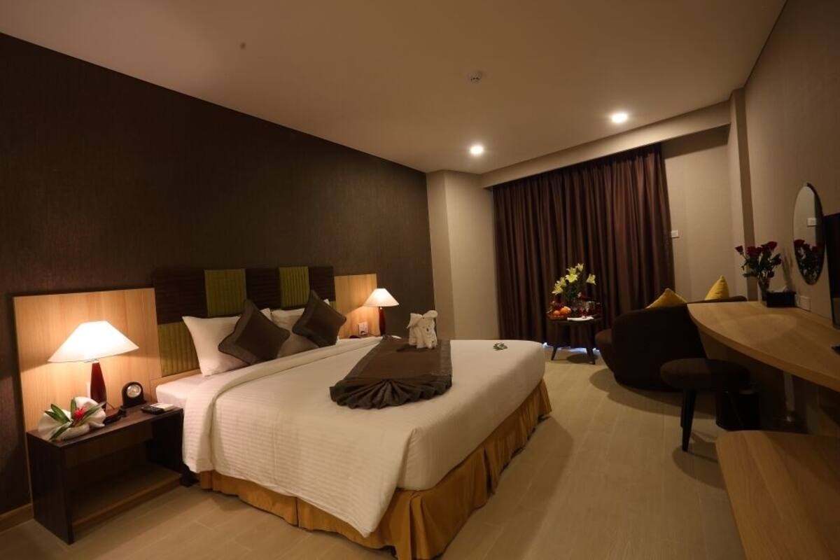 A hotel room with a large bed, bedside tables with lamps, a desk, and a chair.