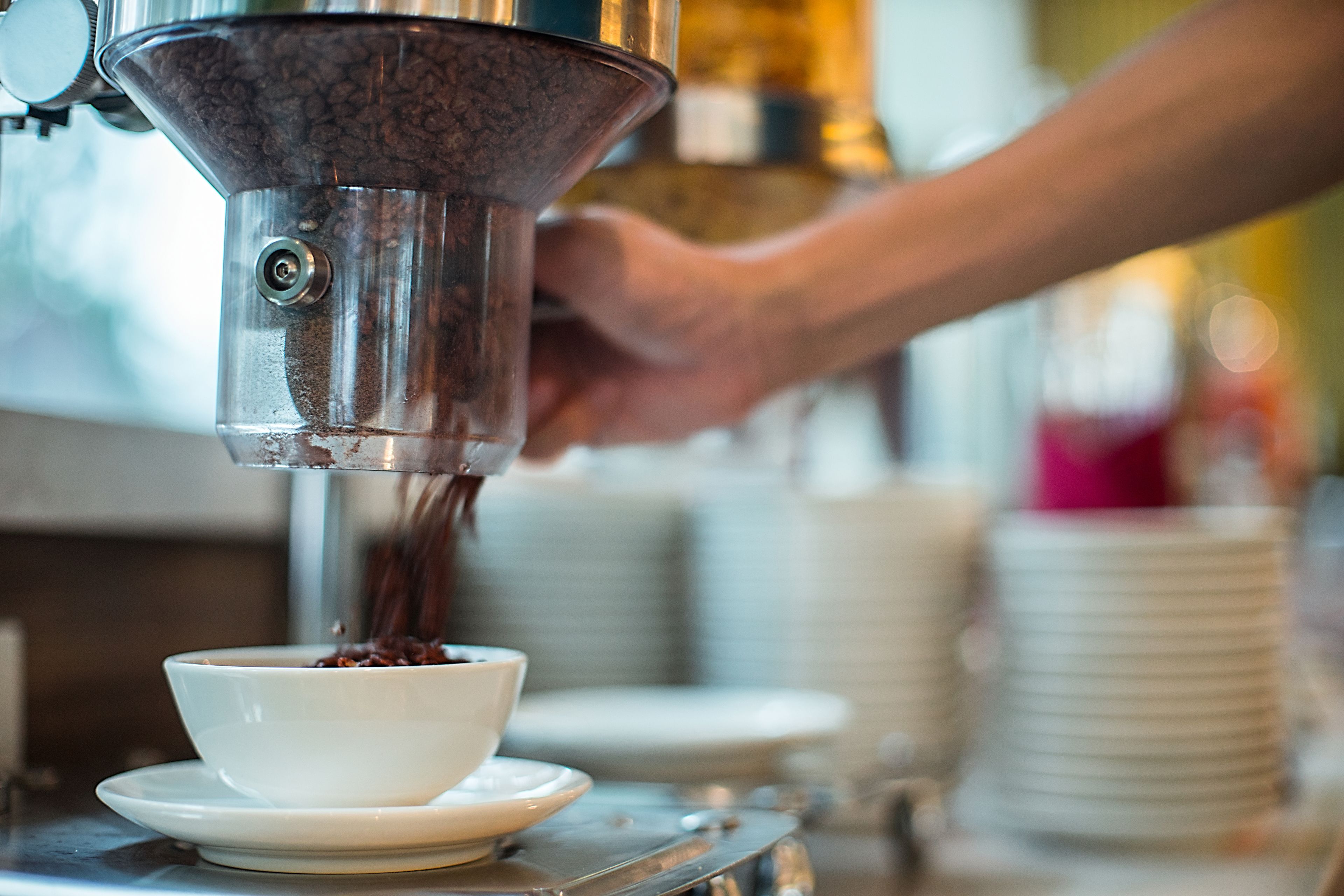 Une machine à café verse du café dans une tasse blanche.
