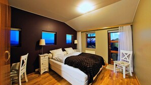 A bedroom with a bed, bedside tables, a chair, and a view through the window.