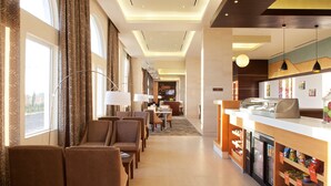 A hotel lobby with seating, a reception area, and a food display. - Hampton Inn by Hilton Silao-Aeropuerto Bajio (Silao)