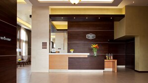 A modern reception area with a wooden reception desk, a hanging light fixture, and a sign that reads "Hampton Inn." - Hampton Inn by Hilton Silao-Aeropuerto Bajio (Silao)