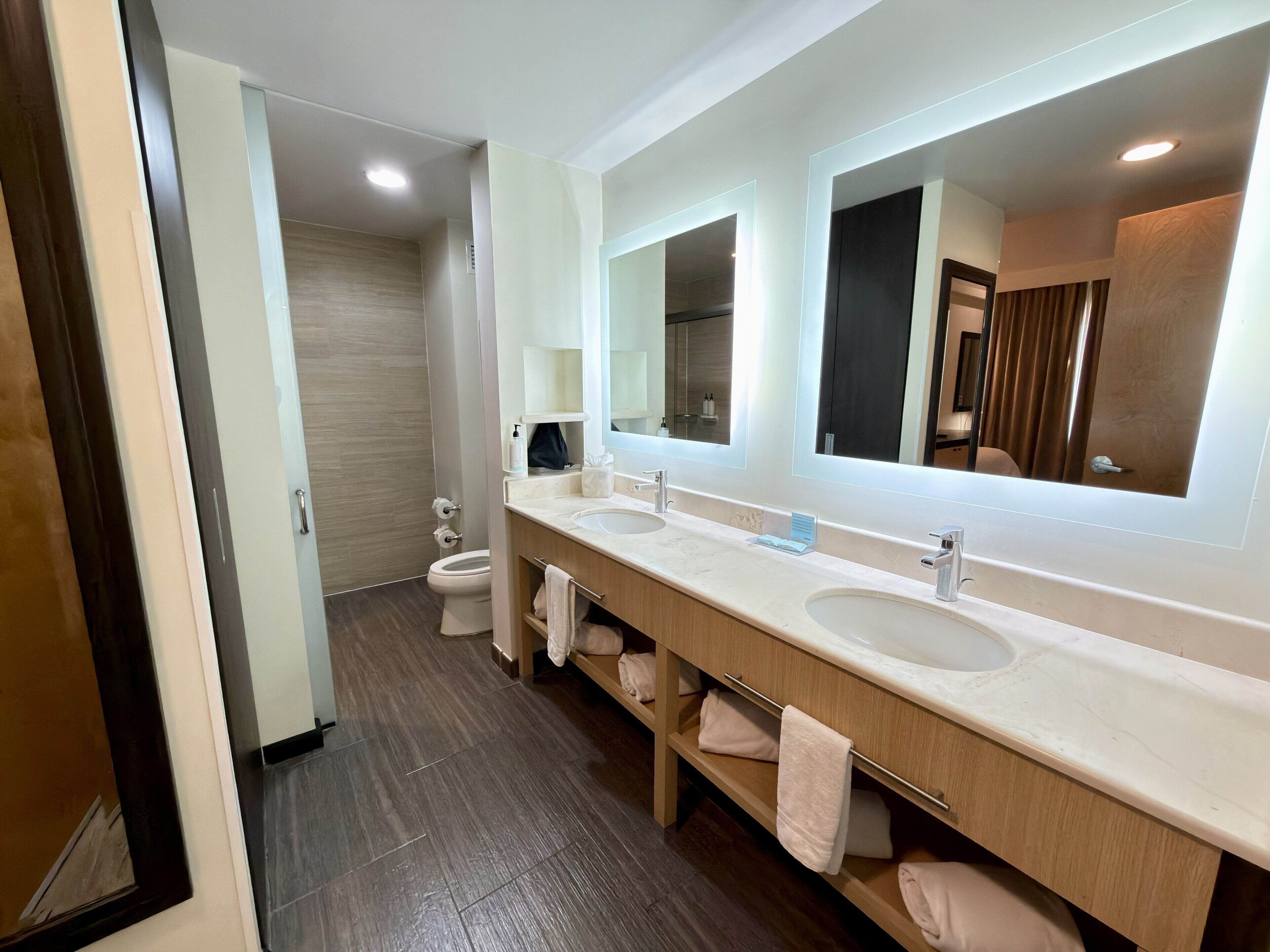 Un baño moderno con dos lavamanos, un espejo grande y un inodoro.