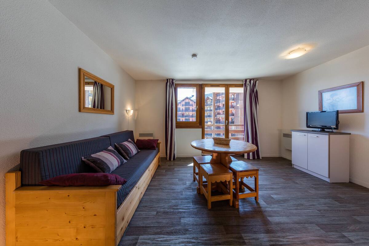 A cozy living room with a sofa, a wooden table, and a television on a cabinet.
