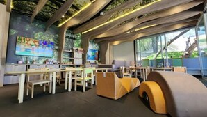 Een moderne bibliotheek met houten tafels en stoelen, boekenplanken en grote ramen.