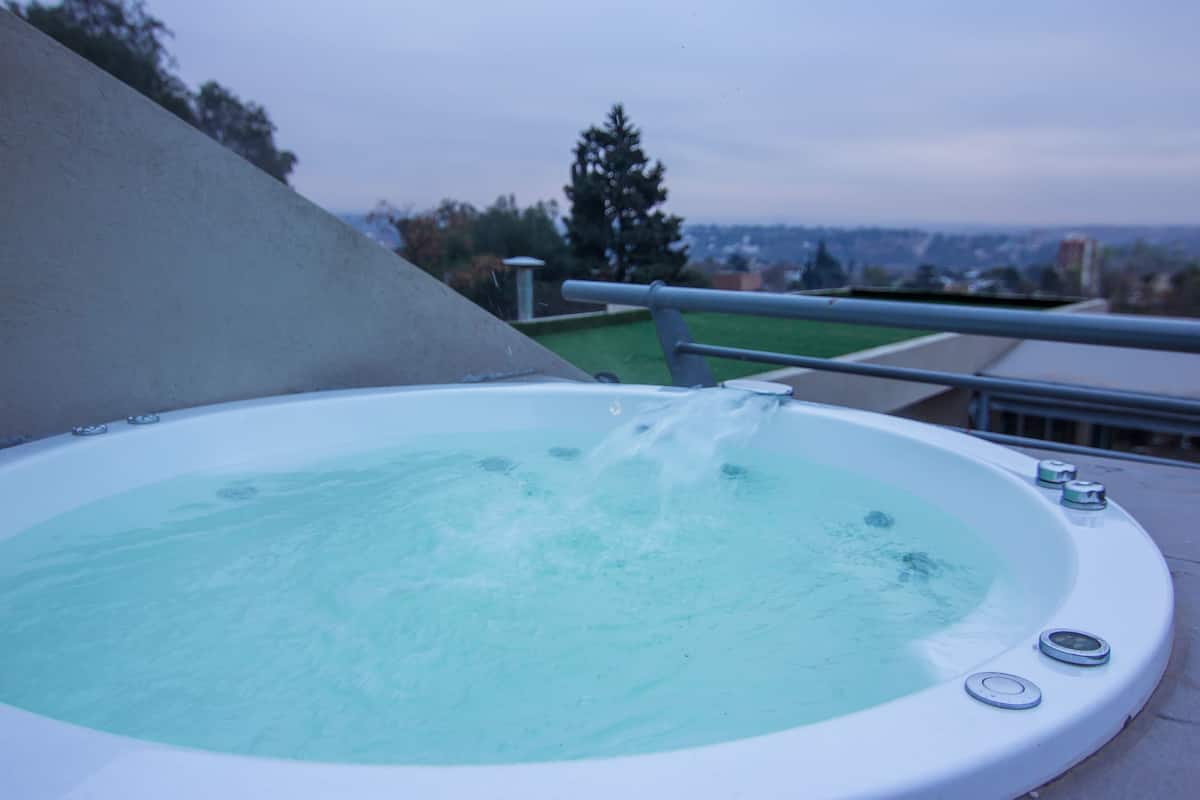 Un bain à remous avec jets d’eau, installé sur un balcon offrant une vue sur la ville.