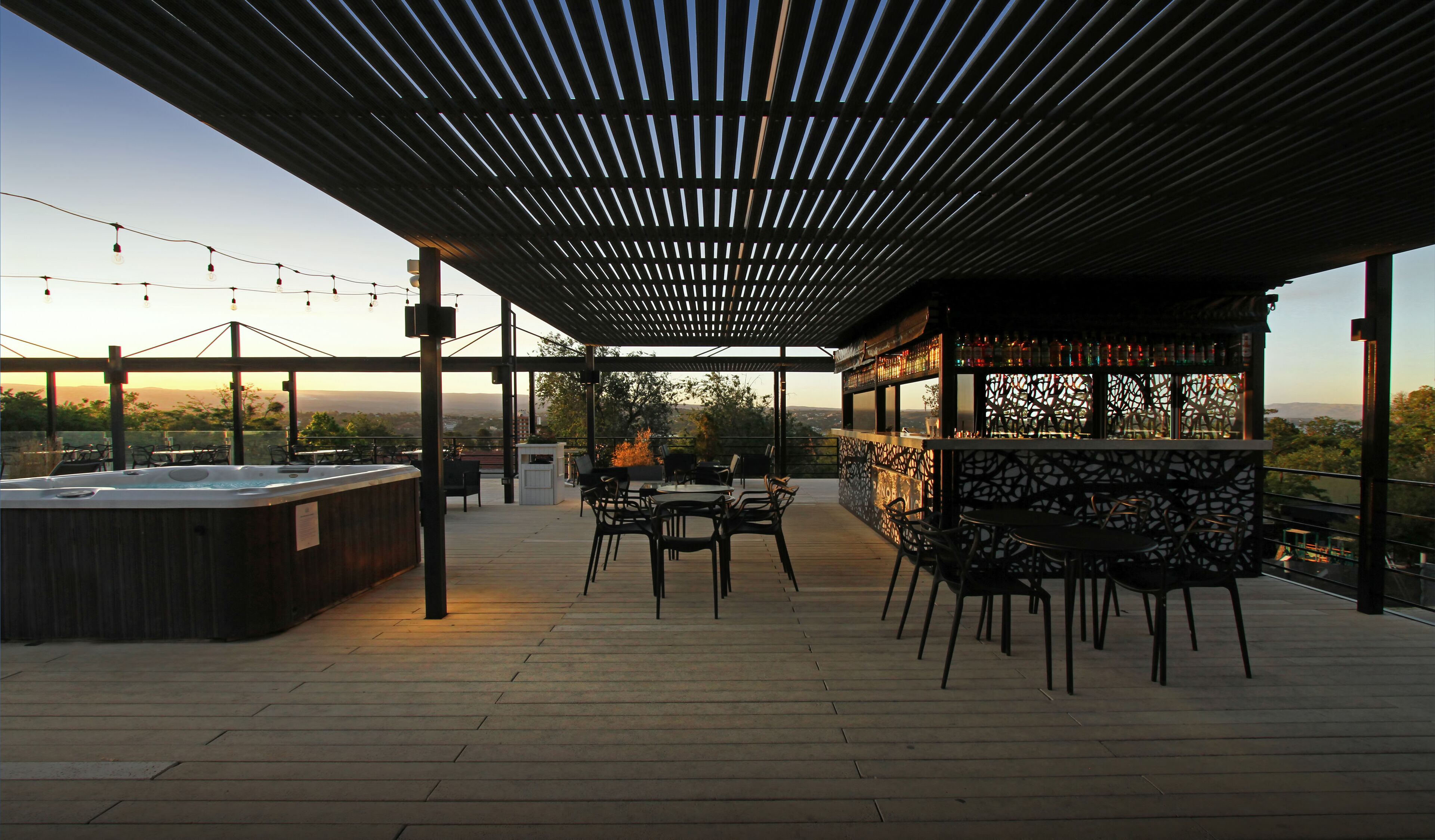 Un patio al aire libre con jacuzzi, mesas y sillas, con vistas panorámicas.
