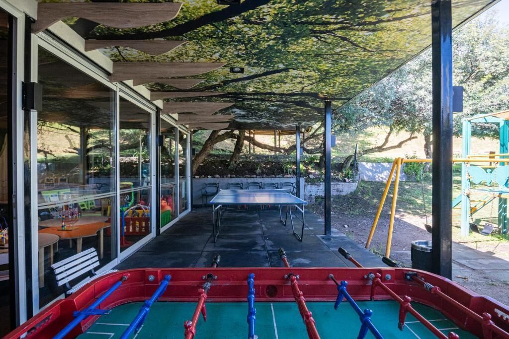 Un patio al aire libre con mesa de fútbol de mesa, mesa de ping pong y un área de estar cubierta con mesas y sillas.