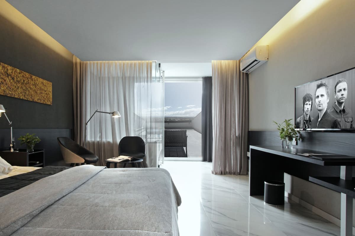 Une chambre d’hôtel moderne, dotée d’un grand lit, d’un bureau, d’une chaise et offrant une vue sur la ville.