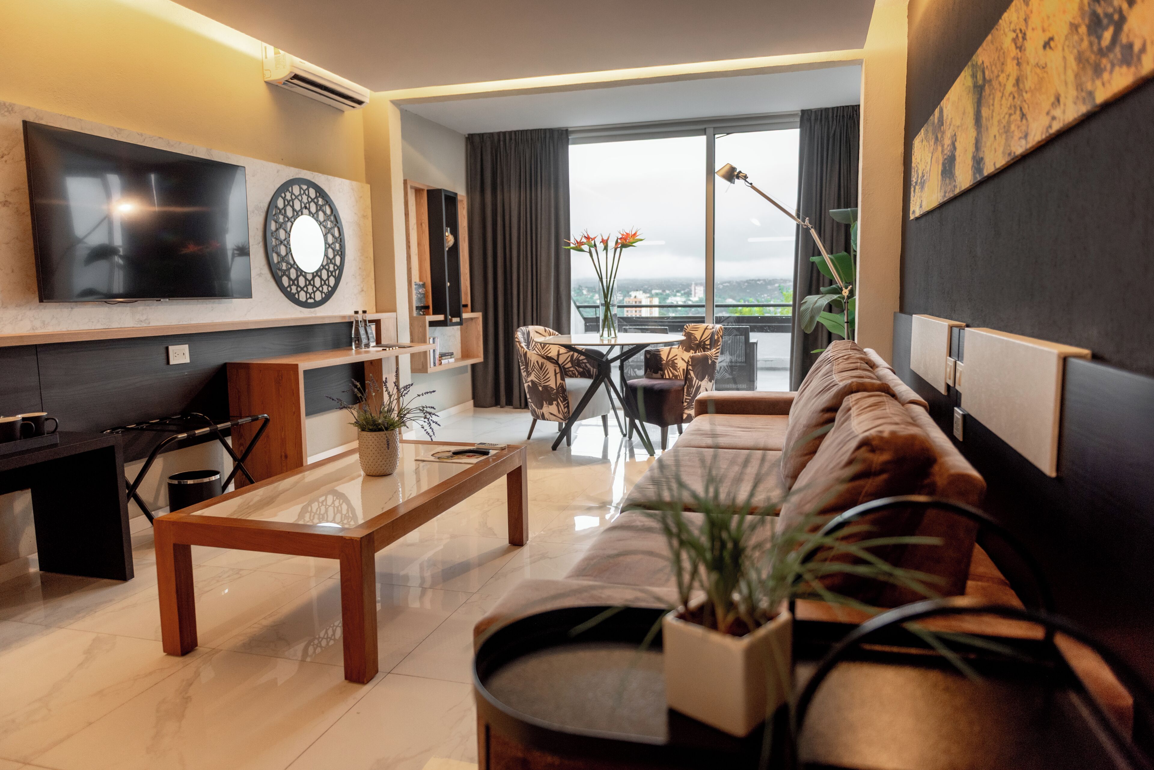 Een moderne woonkamer met een bank, salontafel en een aan de muur bevestigde televisie.