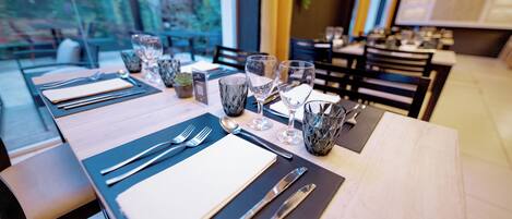 Una mesa de restaurante preparada con cubiertos, vasos y una carta.