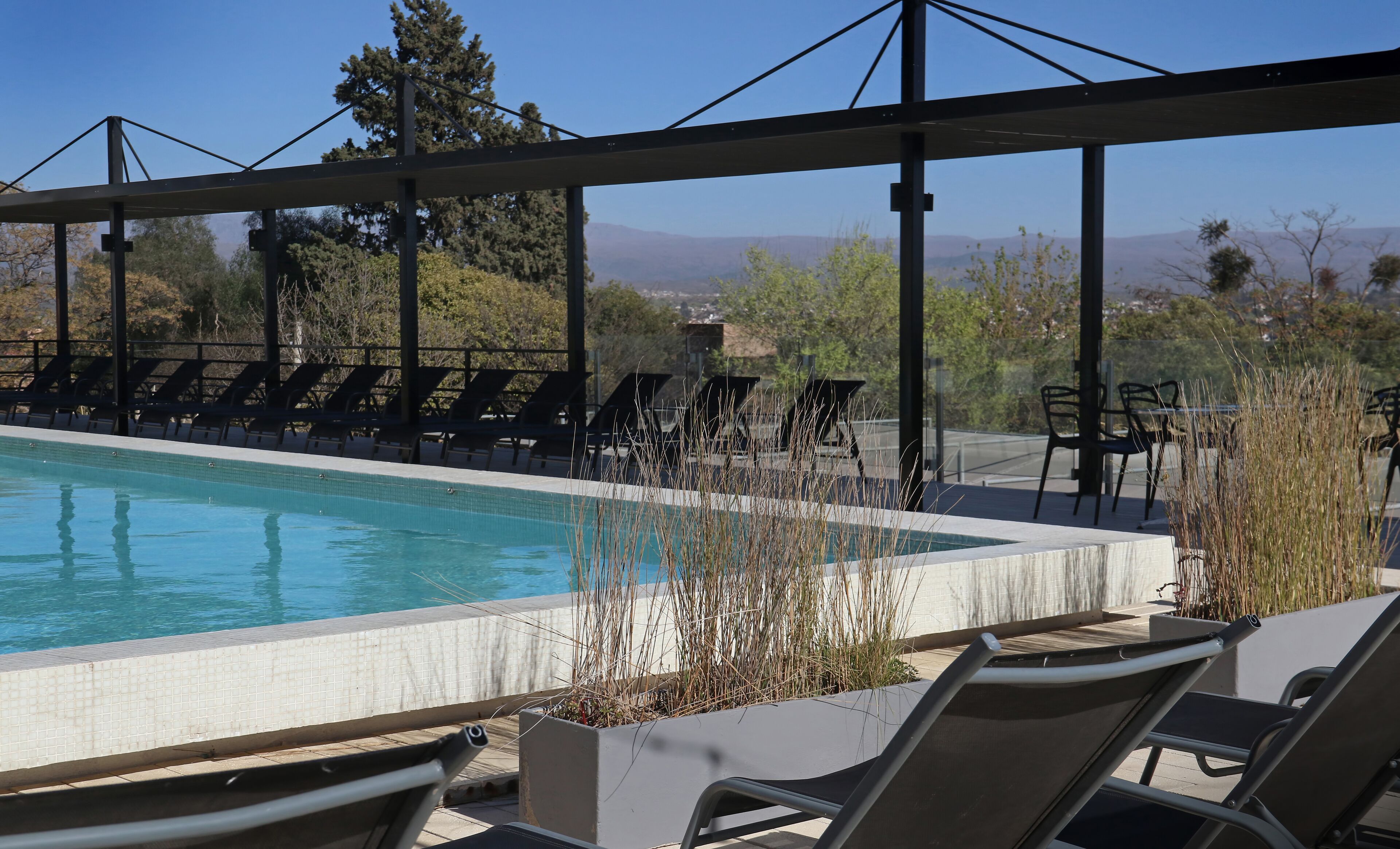 A pool area with lounge chairs and a view of mountains.