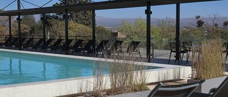 Un área de piscina con sillas de descanso y vistas a montañas.