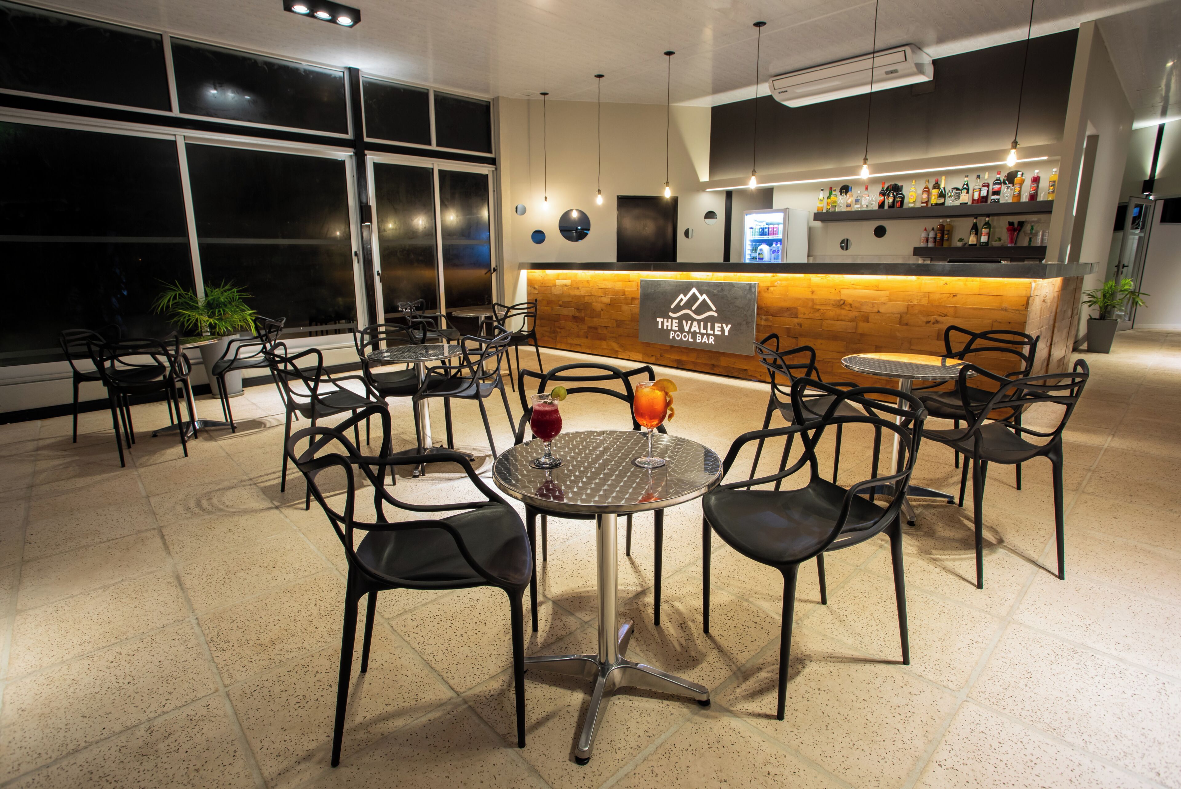 A pool bar area with multiple seating arrangements, a bar counter, and a sign indicating the name of the establishment.