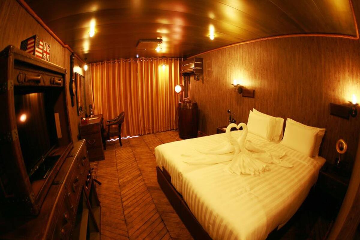 Une chambre d’hôtel avec un grand lit, des murs en bois, un plancher en bois, un bureau avec une chaise et une commode.
