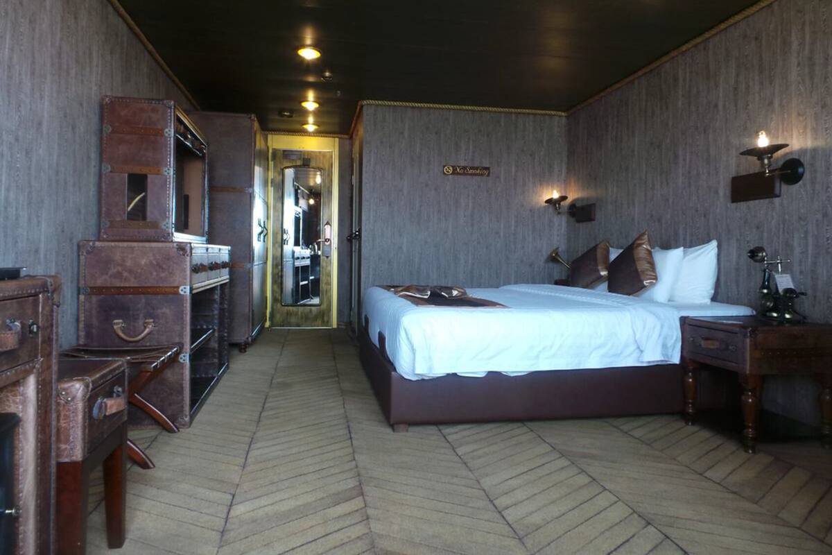 Une chambre d’hôtel avec un grand lit, une commode, un miroir et une valise.