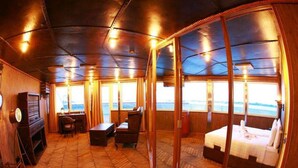 Una cabaña acogedora con suelo de espiga, un escritorio de madera, una silla, una cama y ventanas amplias con vistas al mar.