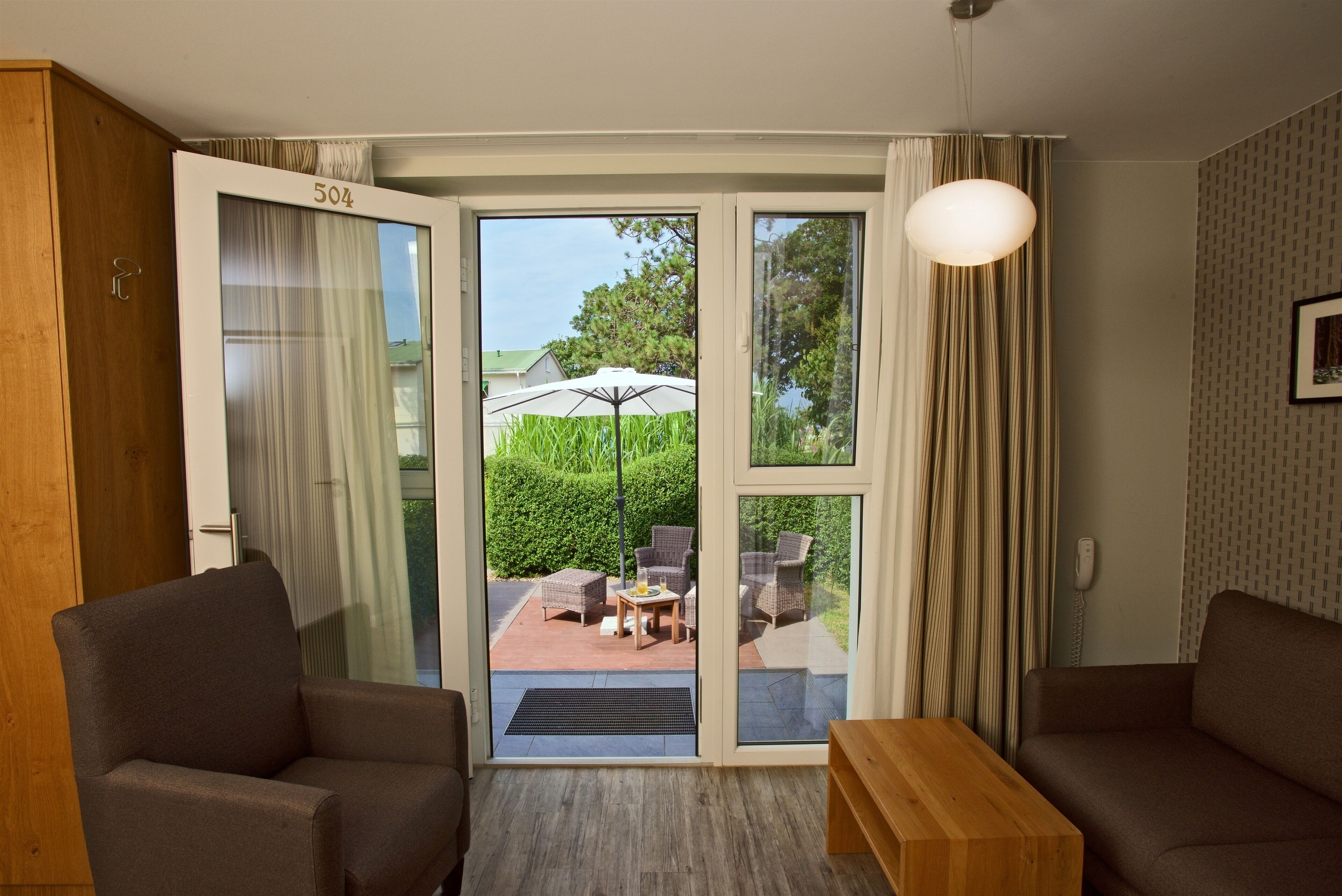 Una habitación con puerta corrediza de vidrio que da a un patio exterior con mobiliario de mimbre y una mesa.