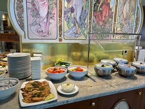 A buffet setup with various dishes and a decorative panel with floral designs. - Panorama Hotel Lohme (Lohme)