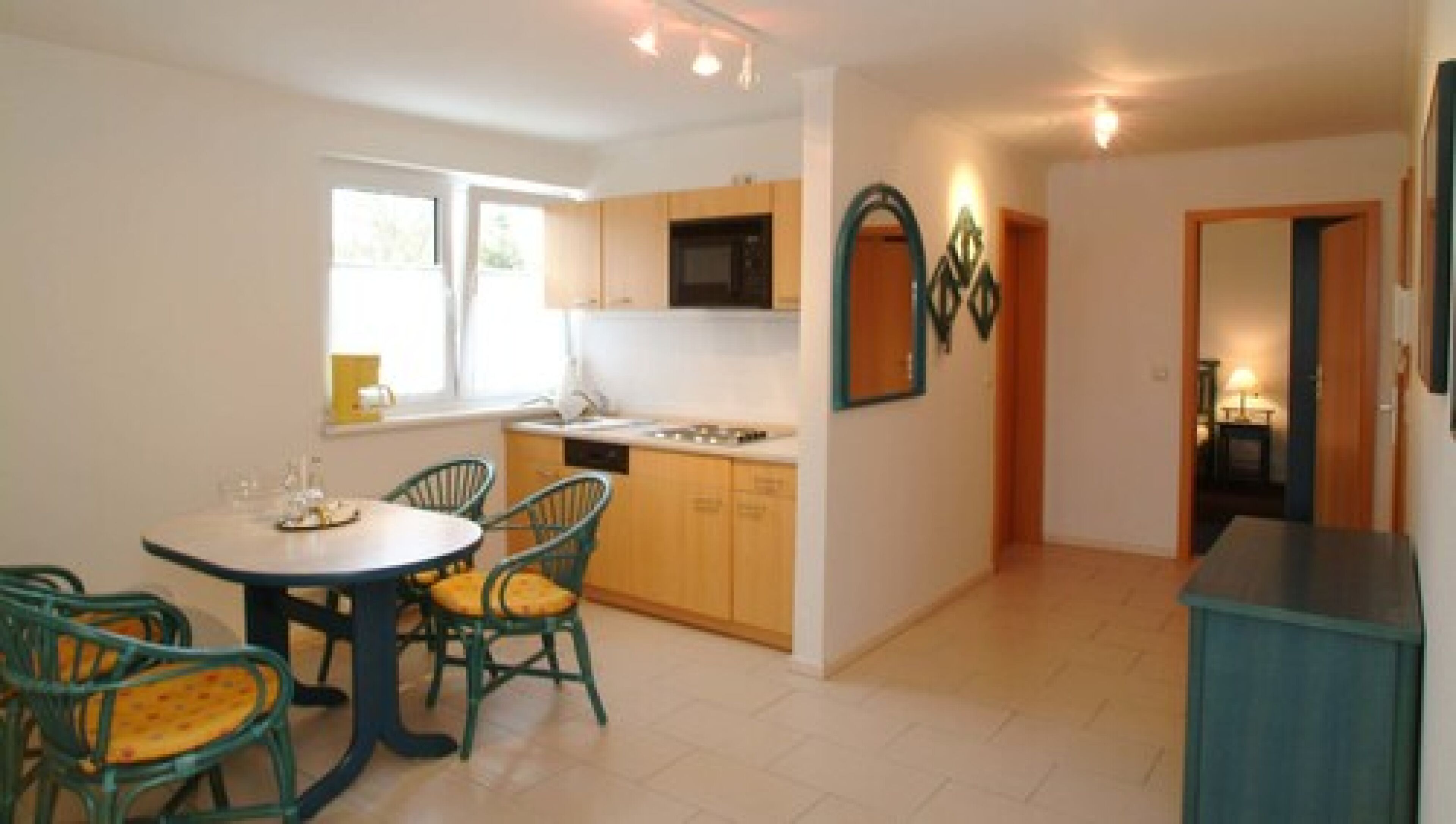 Una cocina moderna con armarios de madera, un microondas y una zona de comedor con una mesa redonda y sillas.