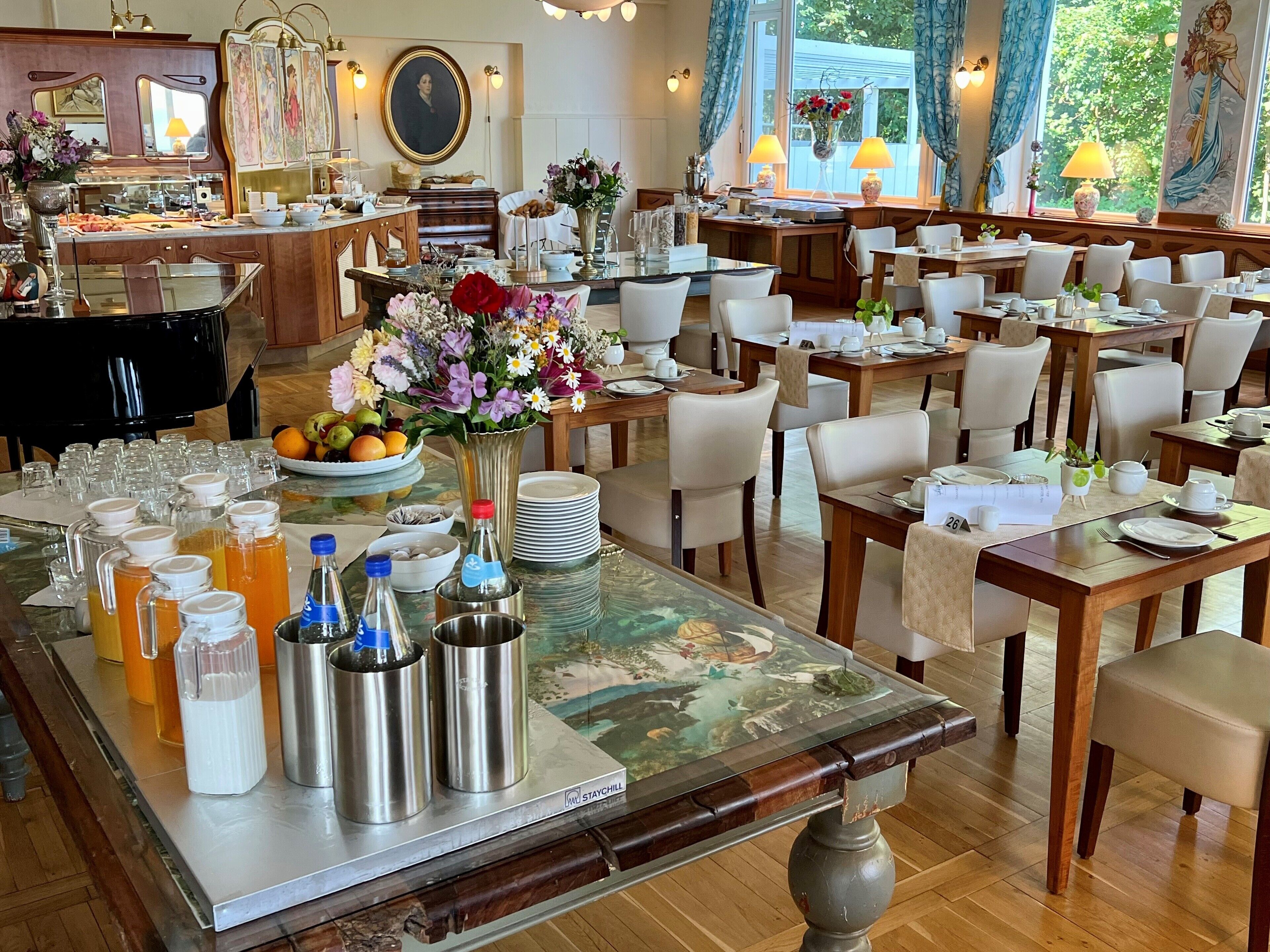 Un espace repas avec plusieurs tables préparées pour le petit-déjeuner, un buffet et une variété de boissons et de plats.