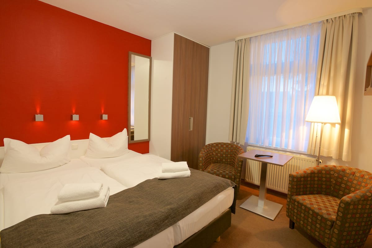 Une chambre d’hôtel avec un grand lit, une chaise, une petite table et une lampe.