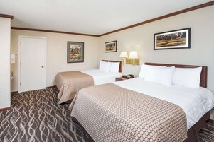 Habitación de hotel con dos camas, alfombra estampada y lámparas fijadas a la pared.