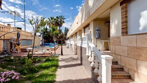 A hotel with a pool, outdoor seating, and a garden with flowers. - ApartHotel Atlas (Torrevieja)