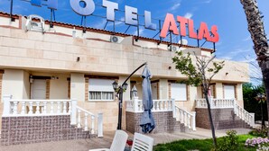A hotel named "HOTEL ATLAS" with a tiled facade, outdoor seating, and a staircase leading to the entrance. - ApartHotel Atlas (Torrevieja)