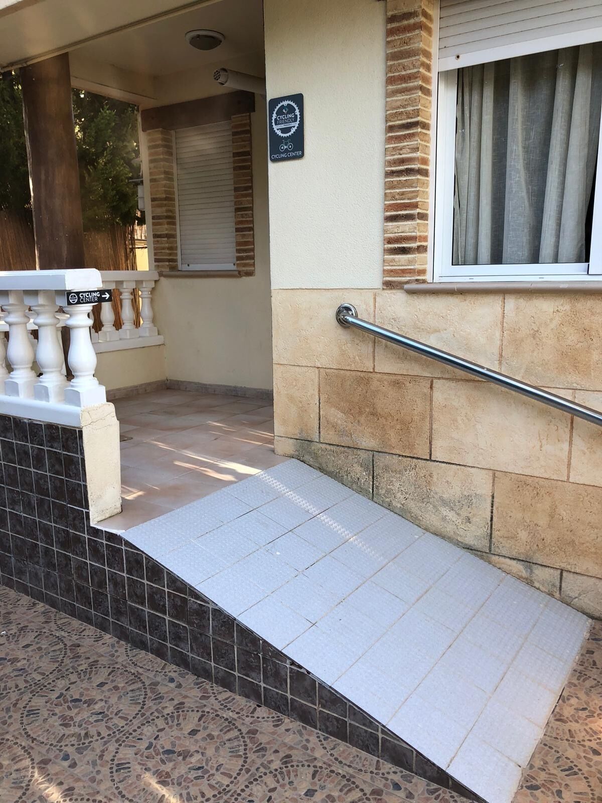 A wheelchair ramp leading to a building entrance with a sign indicating a cycling center.