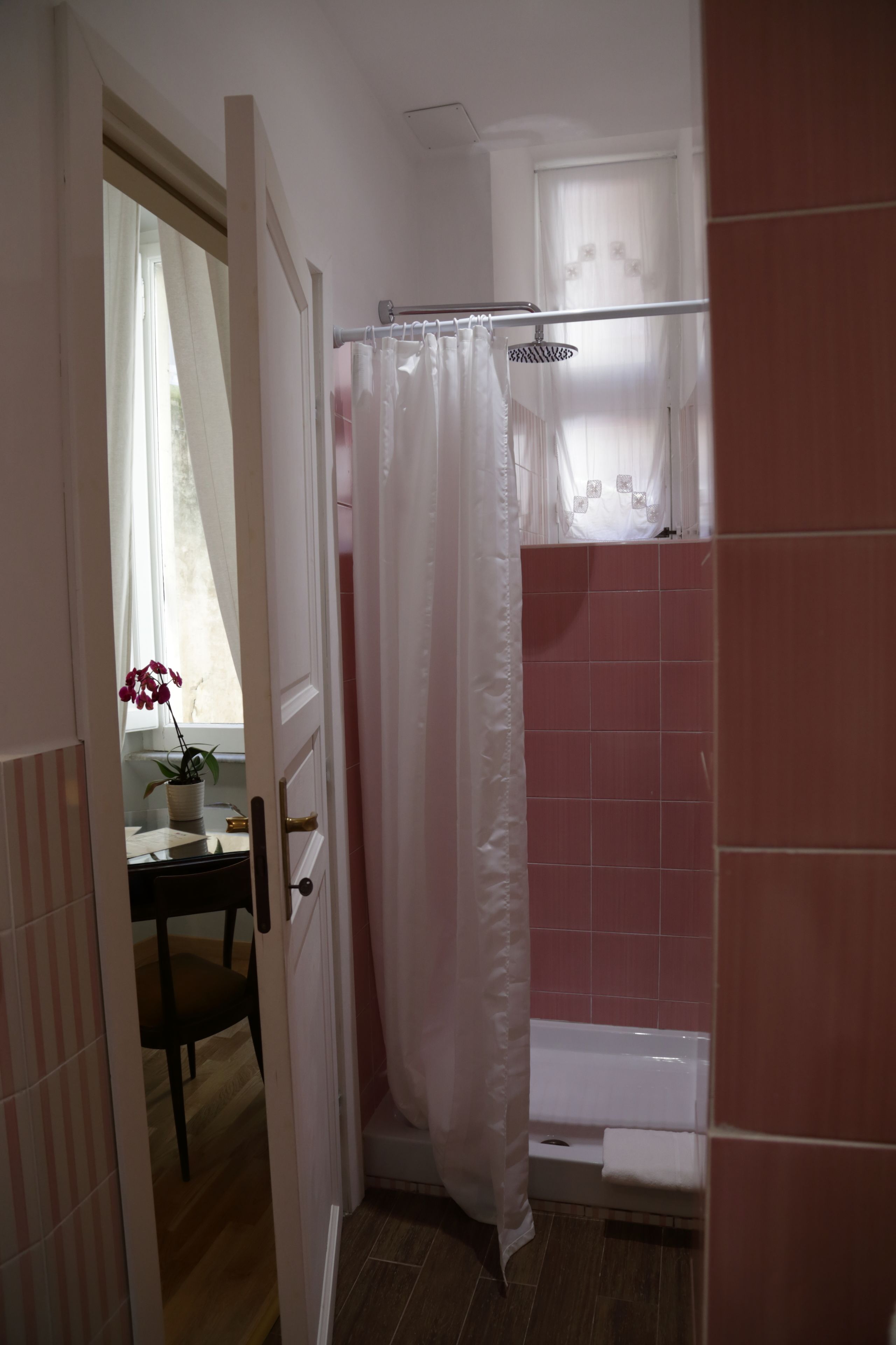 A bathroom with a shower curtain, a bathtub, and a window with curtains.