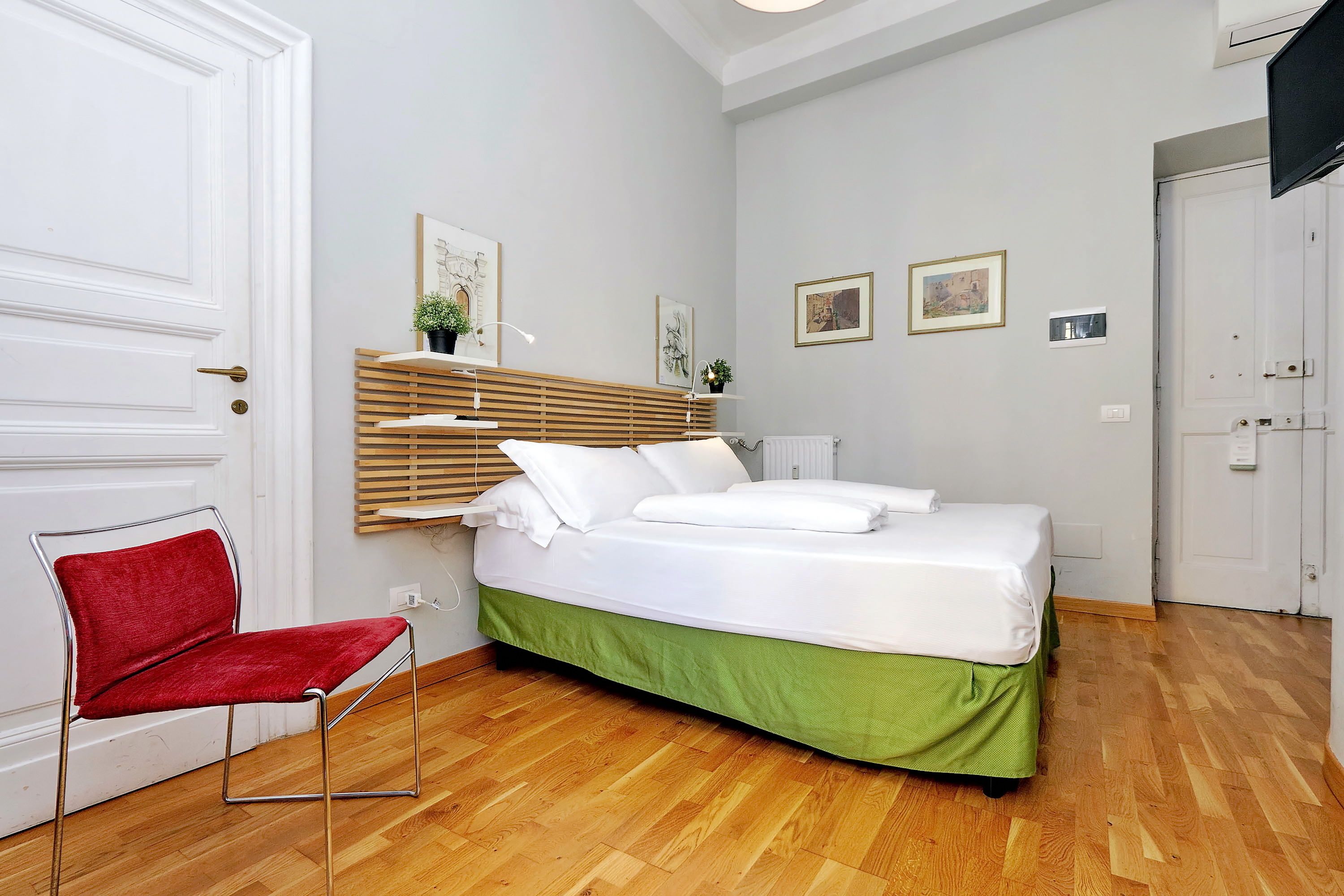 Un dormitorio con una cama, una silla roja y un cabecero de madera.