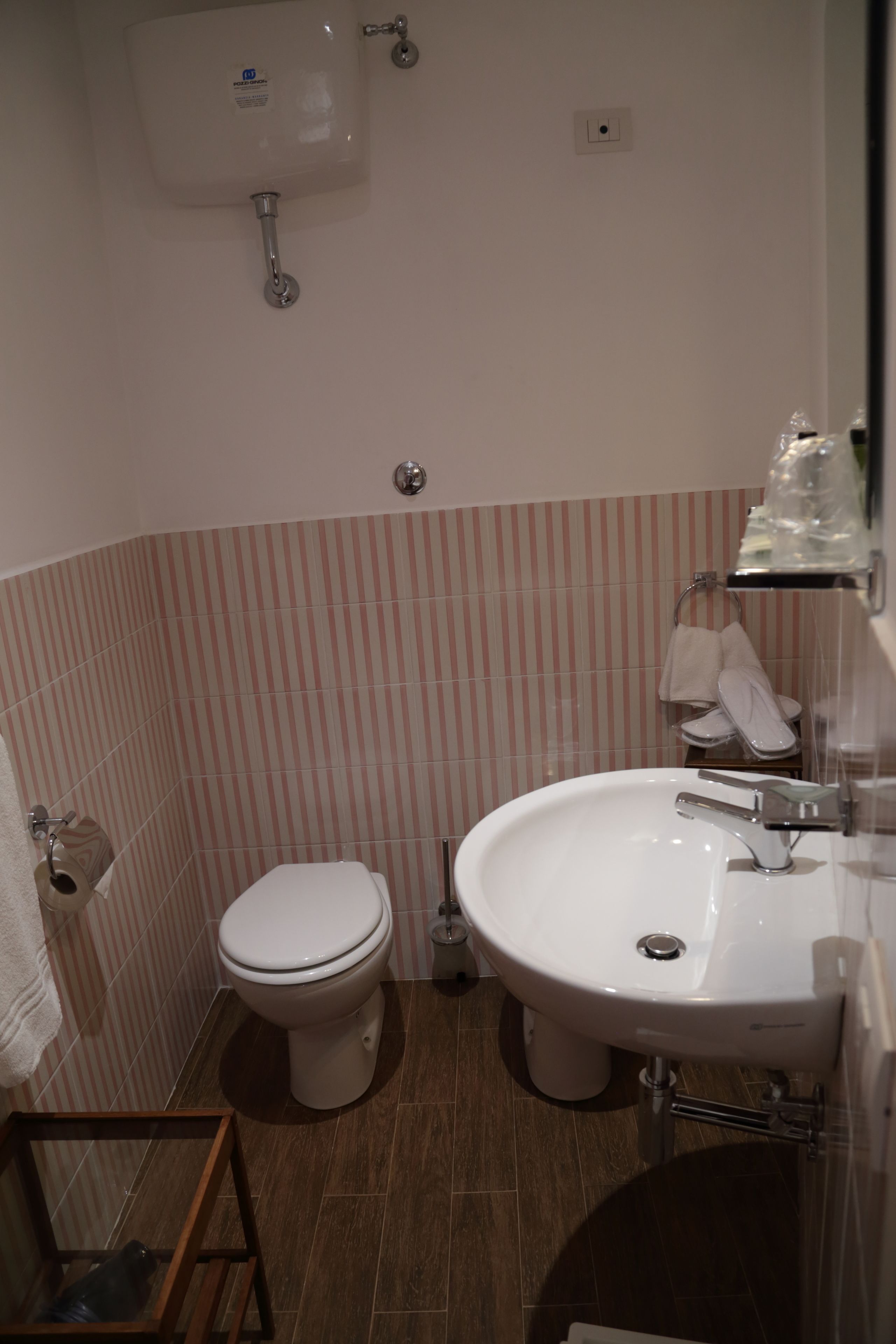 Un baño pequeño con inodoro, lavamanos y azulejos rayados en la pared.