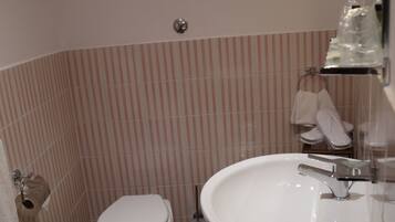 Un baño pequeño con inodoro, lavamanos y azulejos rayados en la pared.