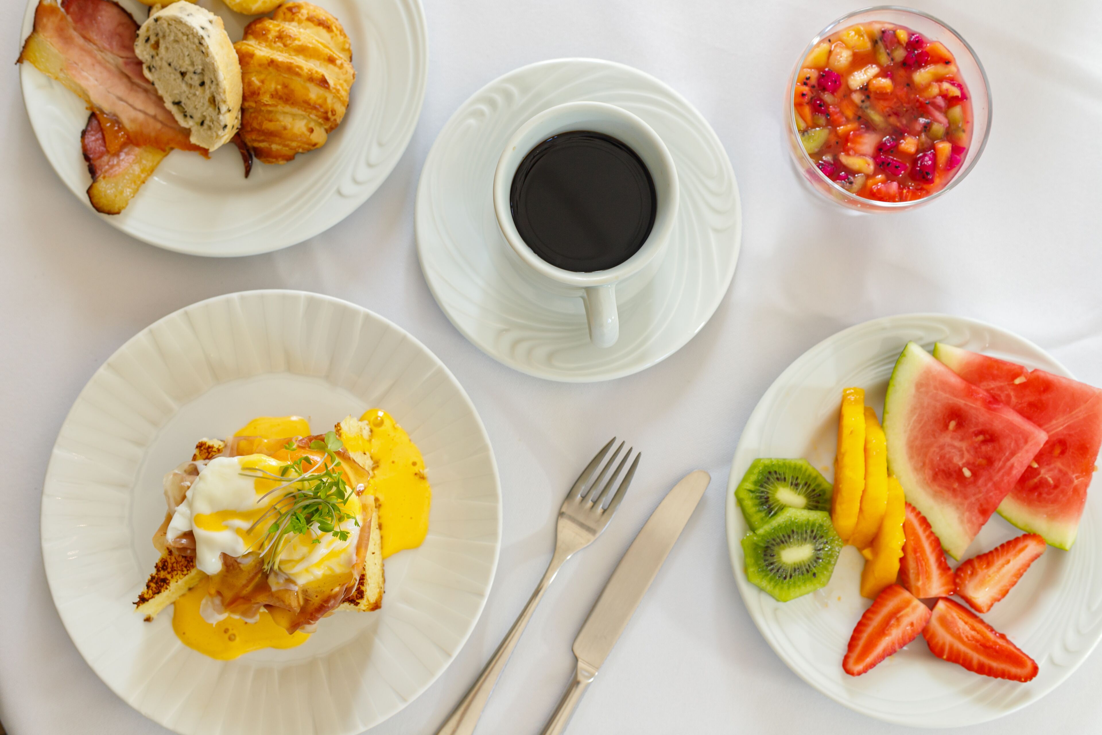 A breakfast setting with plates of food, a cup of coffee, and cutlery.