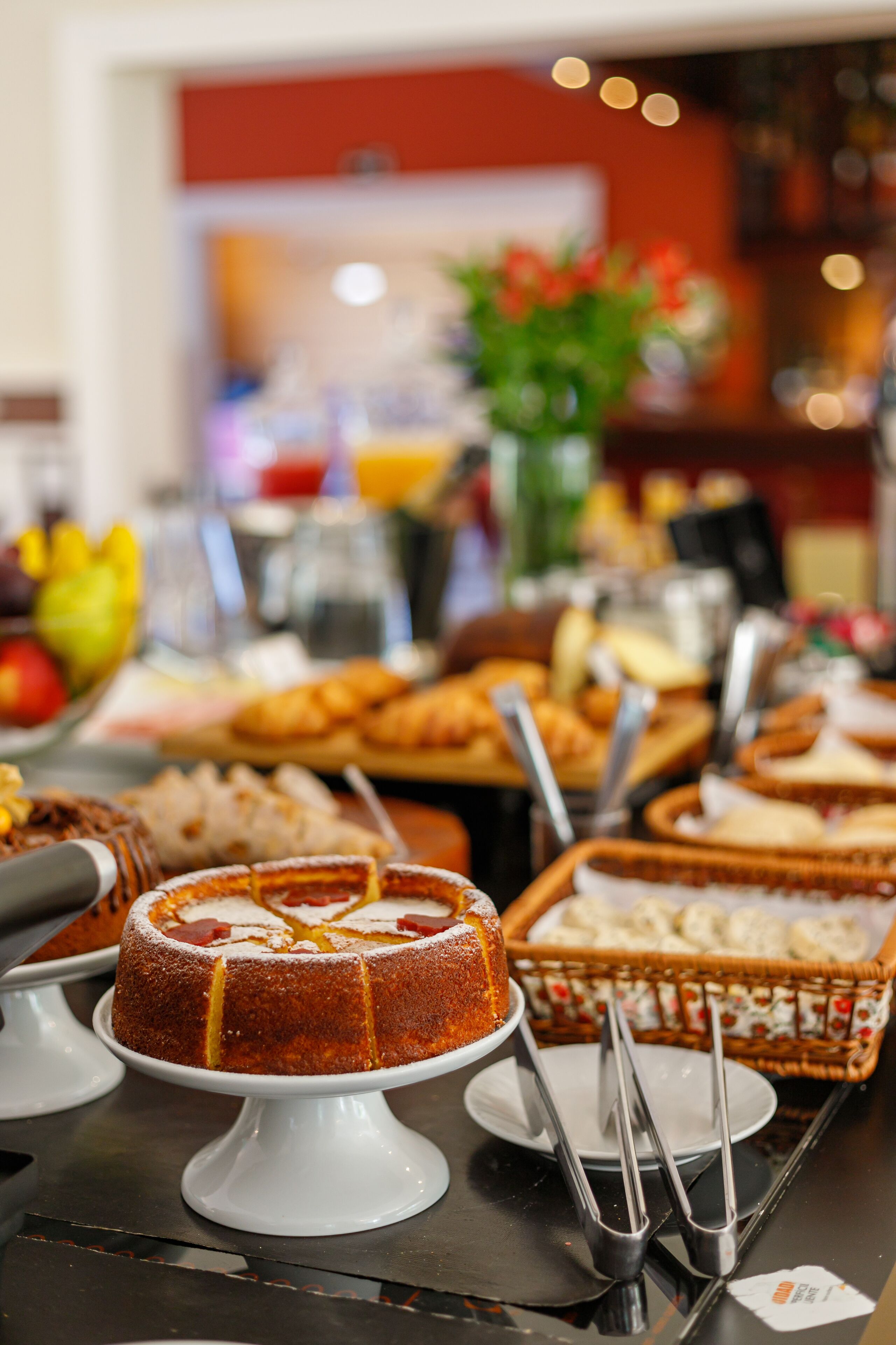 A buffet with various dishes and a cake on a white stand.