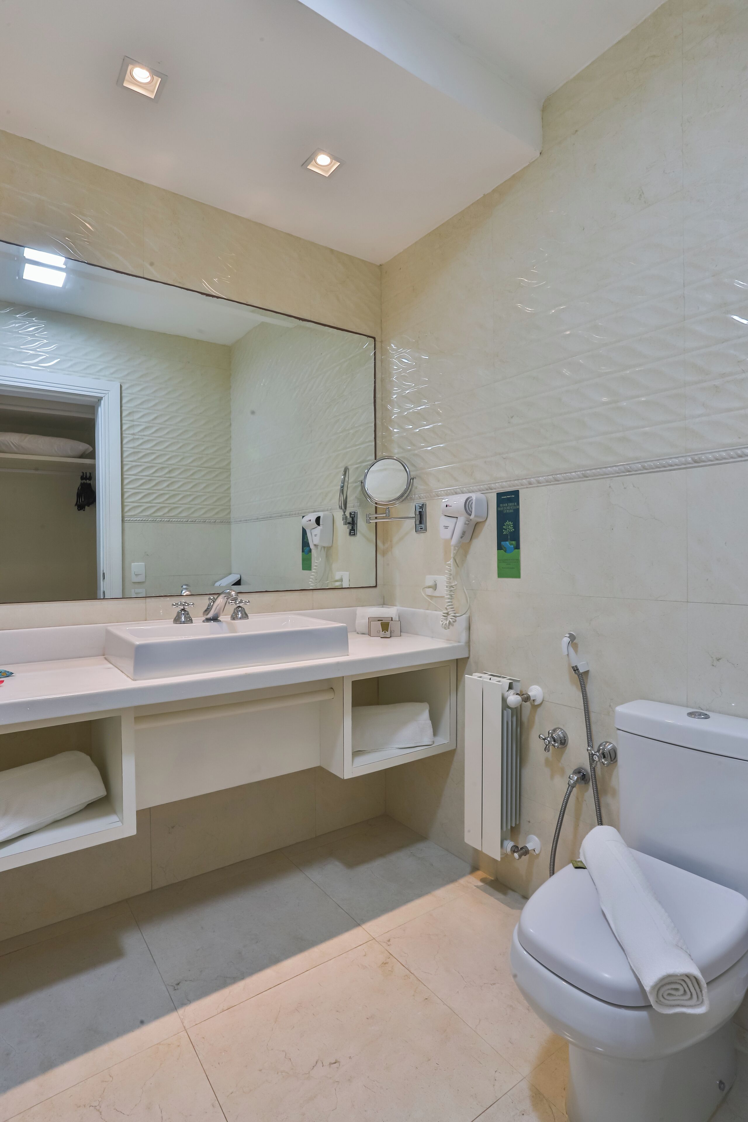 Une salle de bain moderne avec un grand miroir, deux lavabos, des toilettes et une douche.