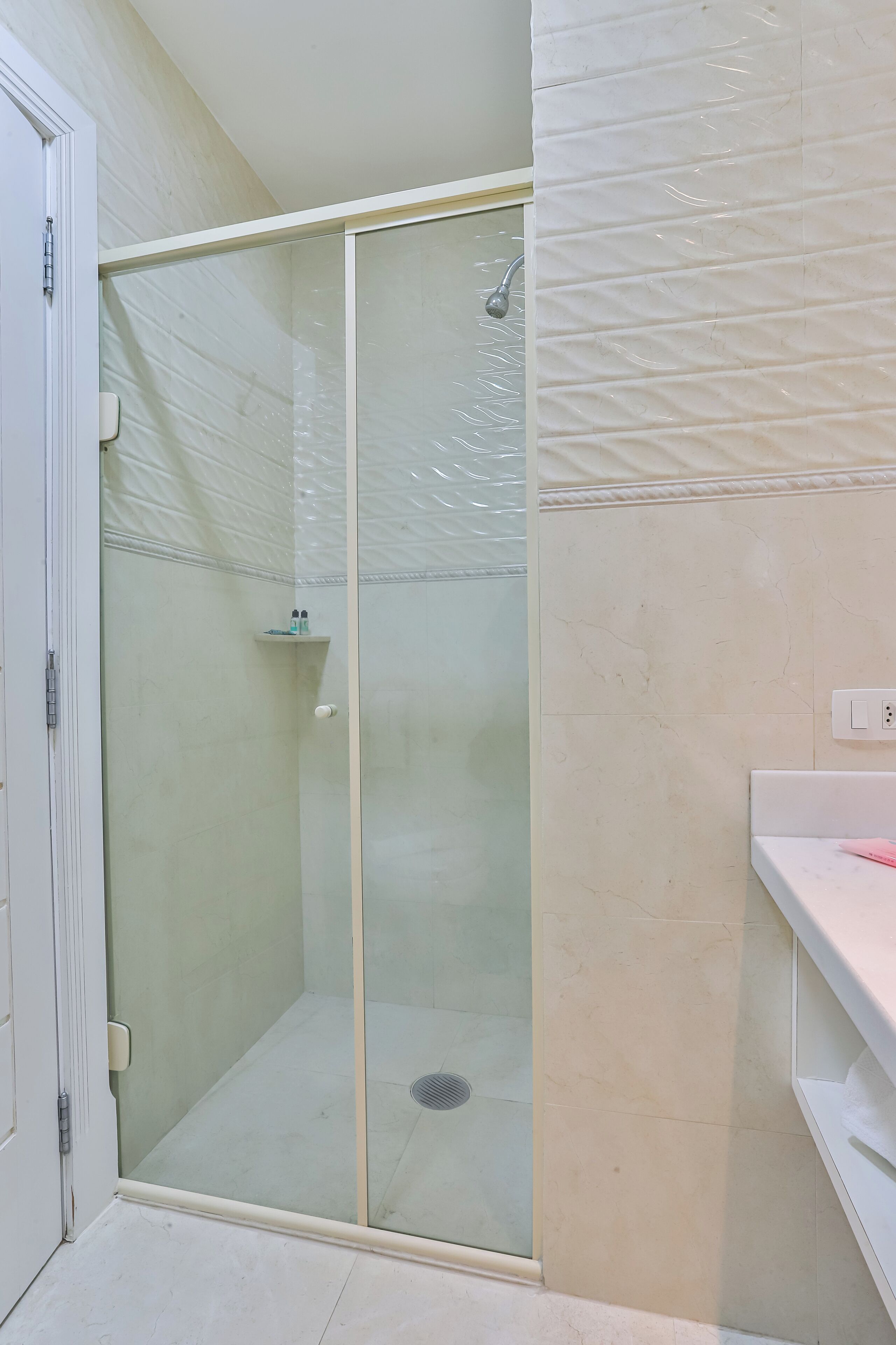 A bathroom with a glass-enclosed shower, a white sink, and a toilet.