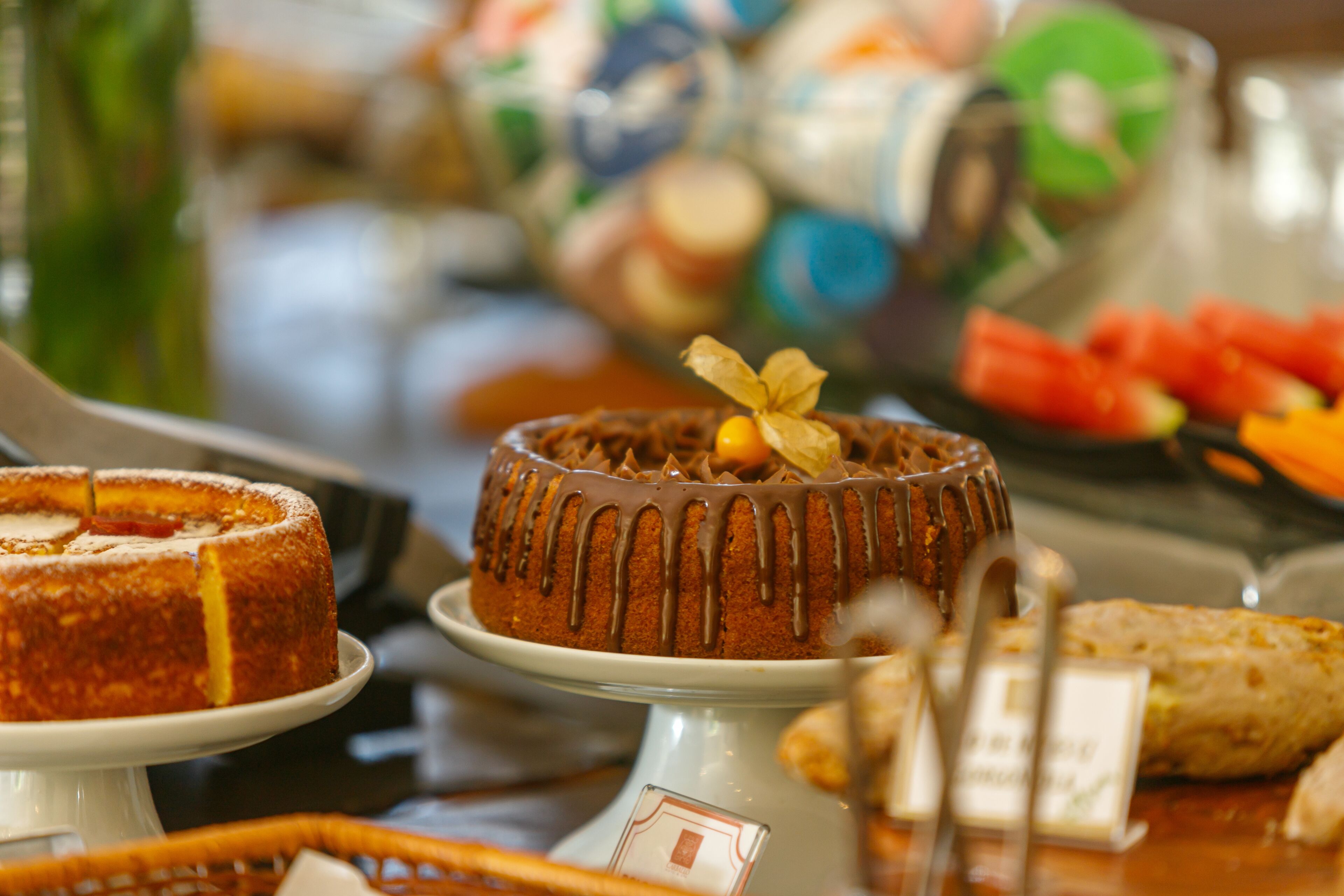 A variety of cakes and pastries on display, including a chocolate cake with a decorative leaf on top.